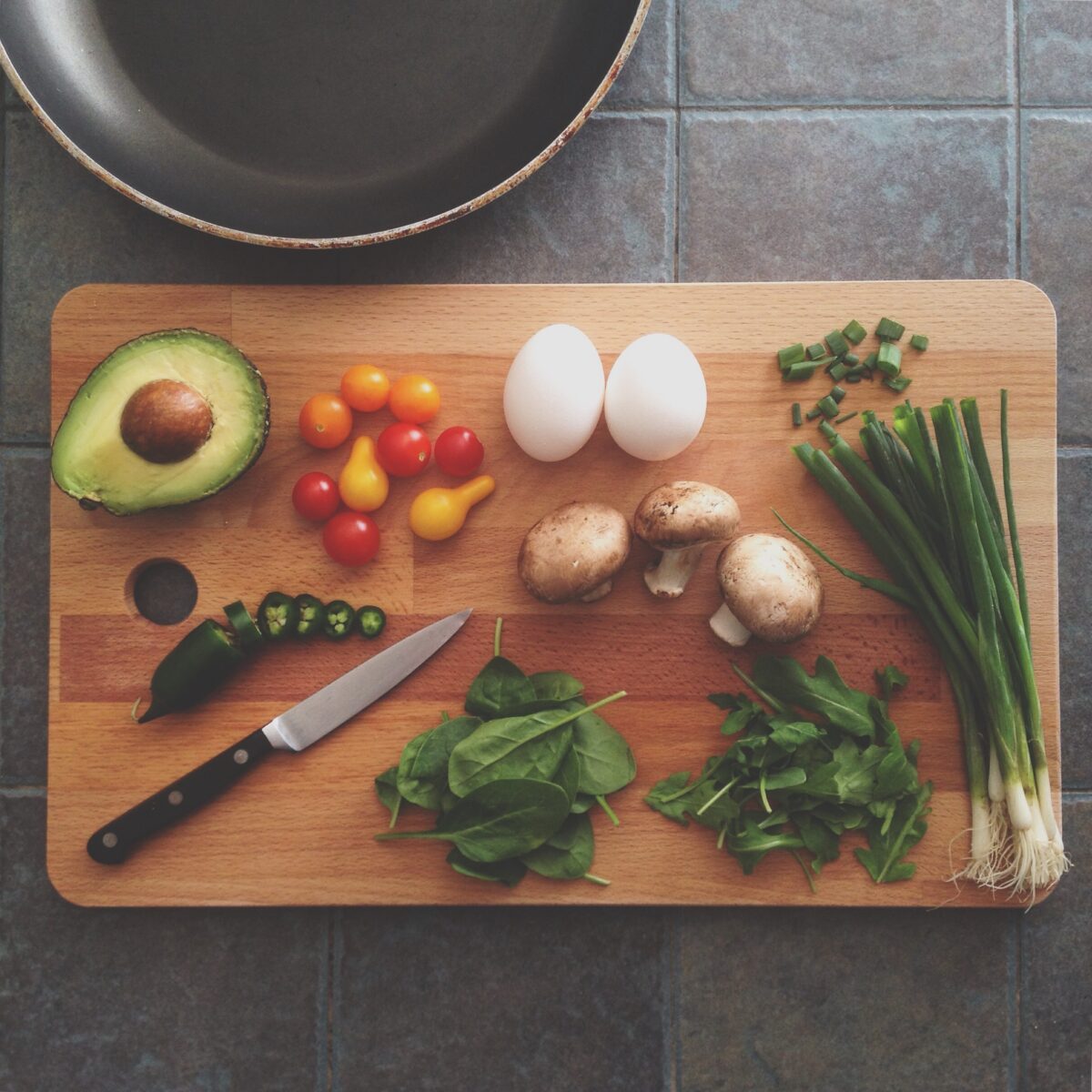 Cutting board with food for a recipe: avocado, egg, spinach